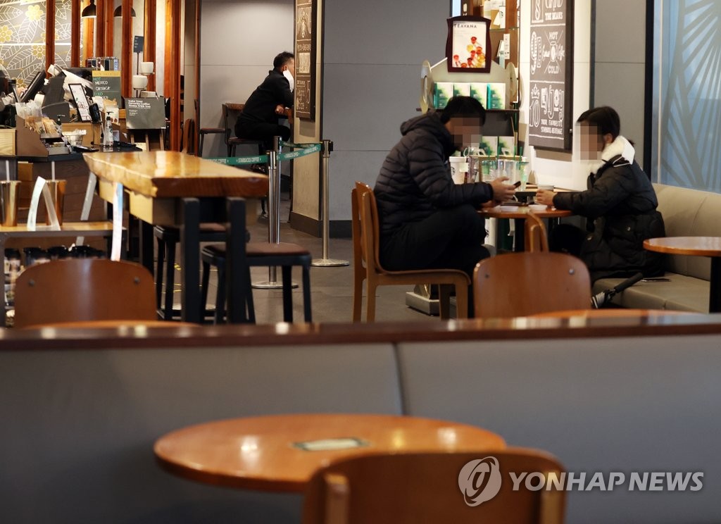 Customers are seated inside a cafe in central Seoul on Jan. 18, 2021, after the government eased COVID-19 restrictions to allow coffee shops to offer dine-in services. (Yonhap)