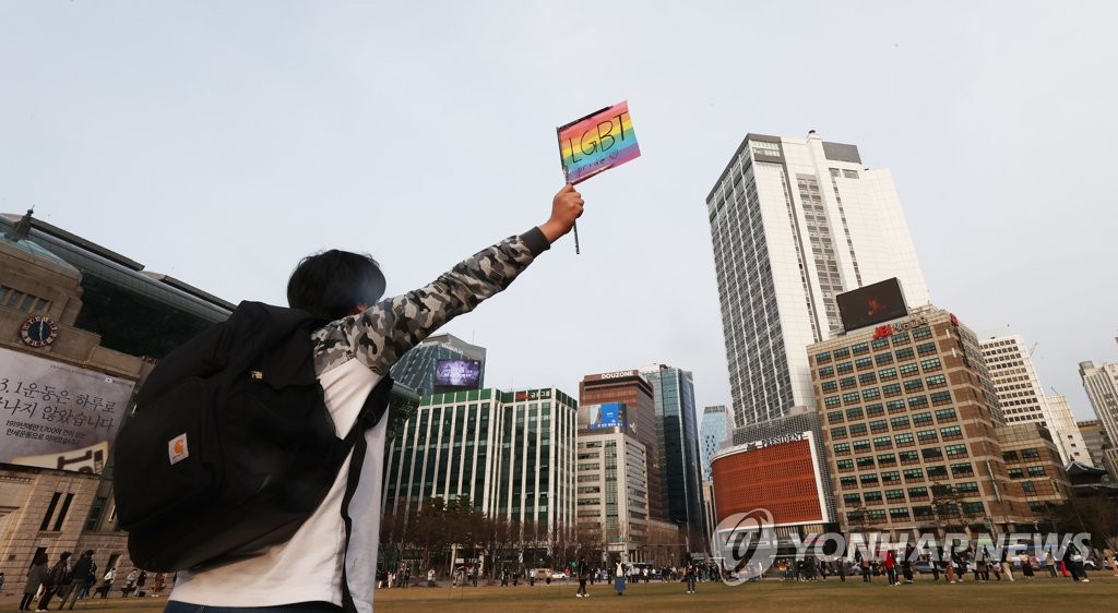 In this file photo, a citizen holds a banner with colors symbolic of the sexual minority community in front of Seoul City Hall on March 6, 2021, at an event to mourn the death of Byun Hee-soo, a former staff sergeant, who was found dead on March 3, about a year after being forcibly discharged by the Army following gender reassignment surgery. (Yonhap) 
