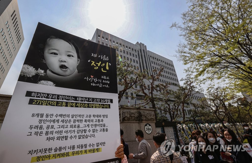 Citizens and activists hold a placard showing a picture of Jung-in, a baby girl who died from months of alleged physical abuse by her adoptive mother now facing trial for murder and other charges, during a rally calling for heavy punishment for the defendant in front of the Seoul Southern District Court on April 7, 2021. (Yonhap)