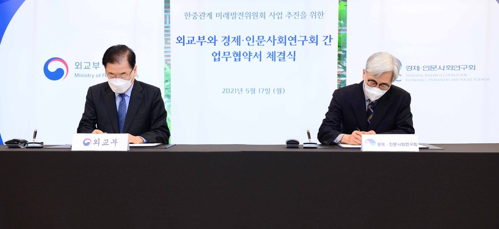 Foreign Minister Chung Eui-yong (L) and Jung Hae-gu, chairperson of the National Research Council for Economics, Humanities and Social Sciences, sign an arrangement on cooperation in pushing for the establishment of a joint committee of civilians between Seoul and Beijing, on May 17, 2021, in this photo provided by the foreign ministry. (PHOTO NOT FOR SALE) (Yonhap)