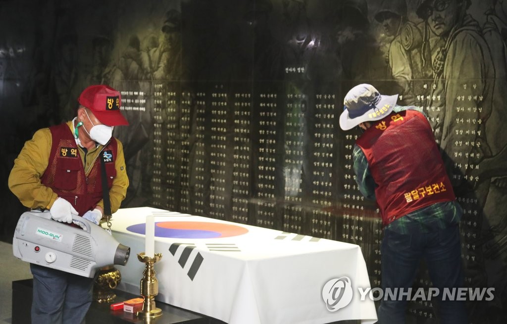 Des travailleurs désinfectent un monument à la mémoire des martyrs patriotiques et des morts à la guerre à Suwon, le jeudi 3 juin 2021, à l'approche du jour du Souvenir. 