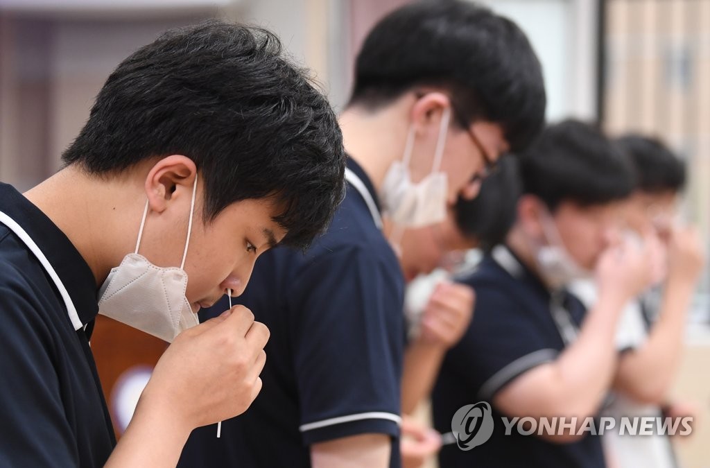 Des élèves du Seoul Robotics High School, dans le sud de Séoul, prélèvent des échantillons de leur nez à l'aide de kits d'auto-test du Covid-19, le 3 juin 2021.