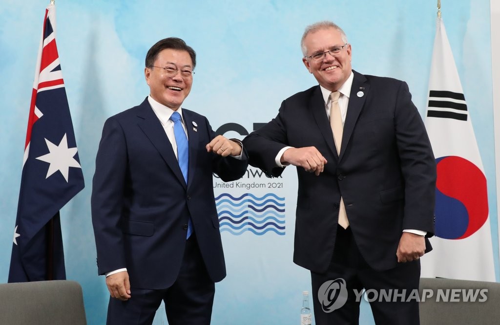 Le président Moon Jae-in (à g.) et le Premier ministre australien Scott Morrison se saluent du coude le samedi 12 juin 2021 lors d'une réunion en Cornouailles, en Grande-Bretagne, en marge du sommet du G7.