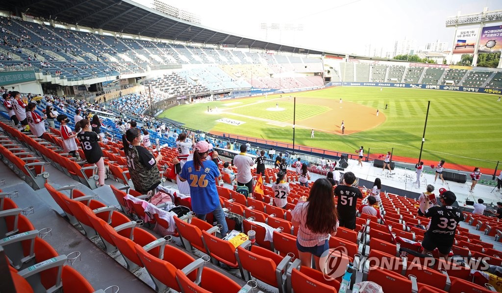Des spectateurs regardent un match de baseball entre les Doosan Bears et les LG Twins au stade de Jamsil, dans le sud-est de Séoul, le dimanche 13 juin 2021. 