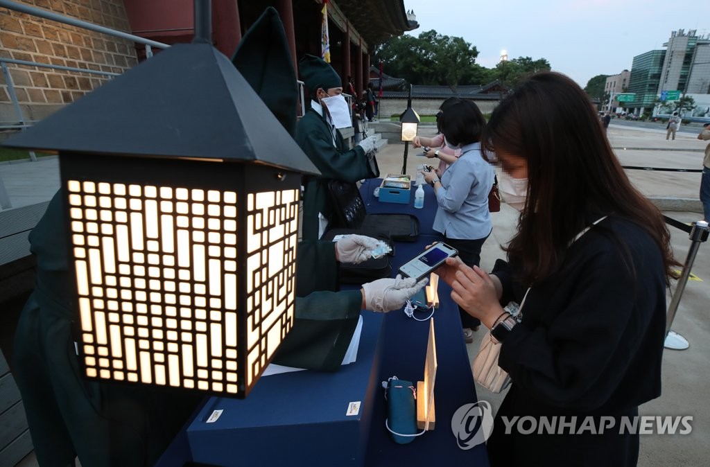 People show their COVID-19 vaccine certificates before entering the Moonlight Tour event at ChangdeokPalace in Seoul on June 23, 2021. (Yonhap)