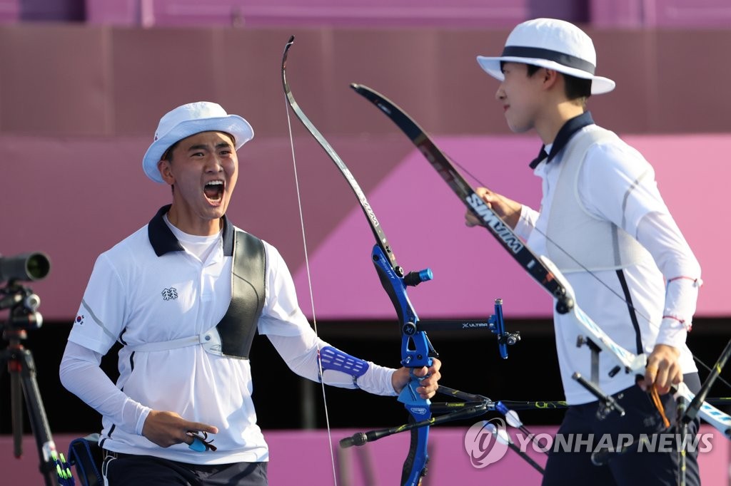 South Korean archers Kim Je-deok (L) and An San celebrate after clinching the gold medal in the mixed team event at the Tokyo Olympics at Yumenoshima Park Archery Field in Tokyo on July 24, 2021. (Yonhap)