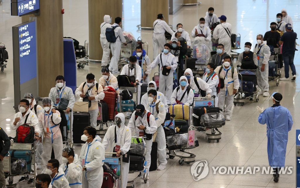 仁川国際空港に到着した外国人。防護服を着用している人が多い＝２６日、仁川（聯合ニュース）