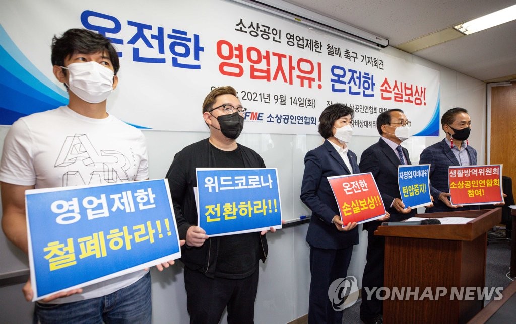 Members of the Korea Federation of Micro Enterprise hold a press conference at the National Assembly on Sept. 14, 2021, to demand the government scrap antivirus restrictions and compensate them for business losses. (Pool photo) (Yonhap)