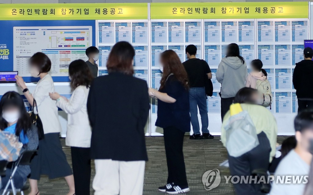 Los jóvenes demandantes de empleo observan un tablón de anuncios con información laboral, en una feria de empleo, el 7 de octubre de 2021, en Goyang, al norte de Seúl.