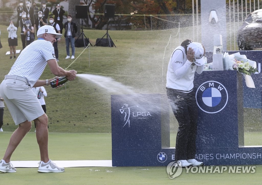 Ko Jin-young of South Korea (R) is doused with champagne sprayed by her caddie, Dave Brooker, after winning the BMW Ladies Championship at LPGA International Busan in Busan, some 450 kilometers southeast of Seoul, on Oct. 24, 2021. (Yonhap)