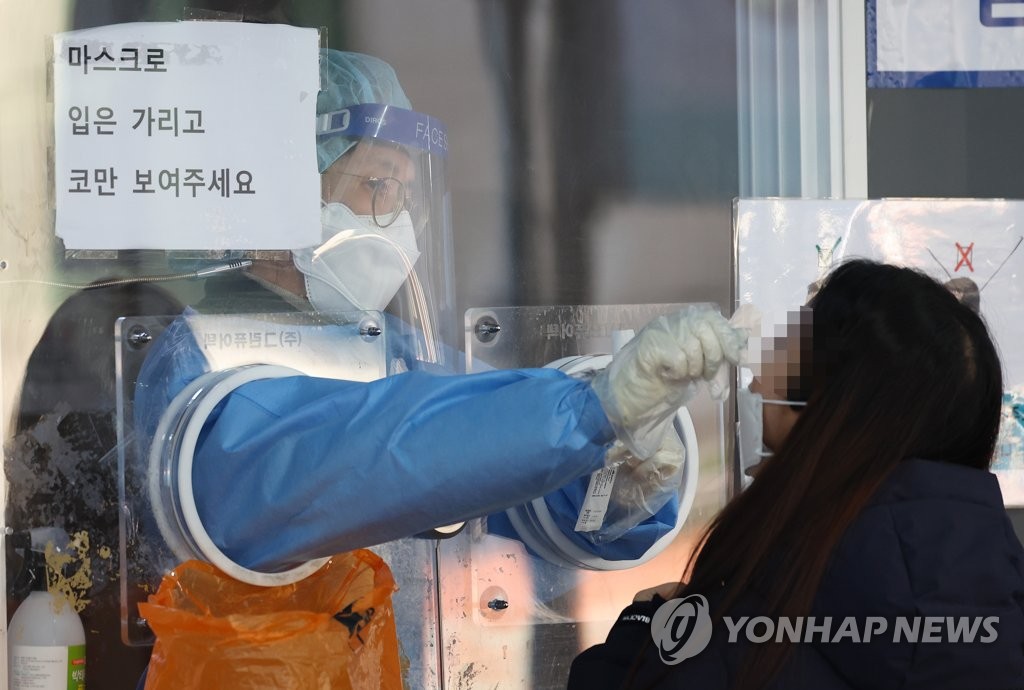 A health worker conducts a COVID-19 test on a citizen at a makeshift testing site in front of Seoul Station in Seoul on Nov. 26, 2021. (Yonhap)