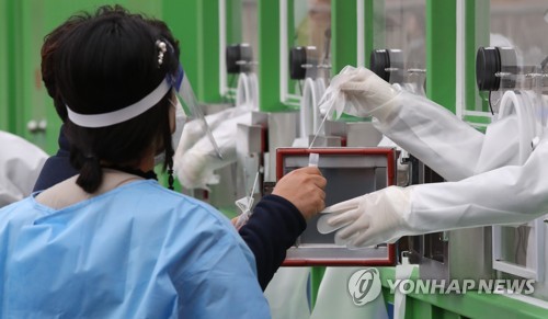 La foto, sin fechar, muestra a trabajadores médicos realizando pruebas de COVID-19 a ciudadanos, en un centro de exámenes provisional, en el sur de Seúl, en medio del repunte de las infecciones.