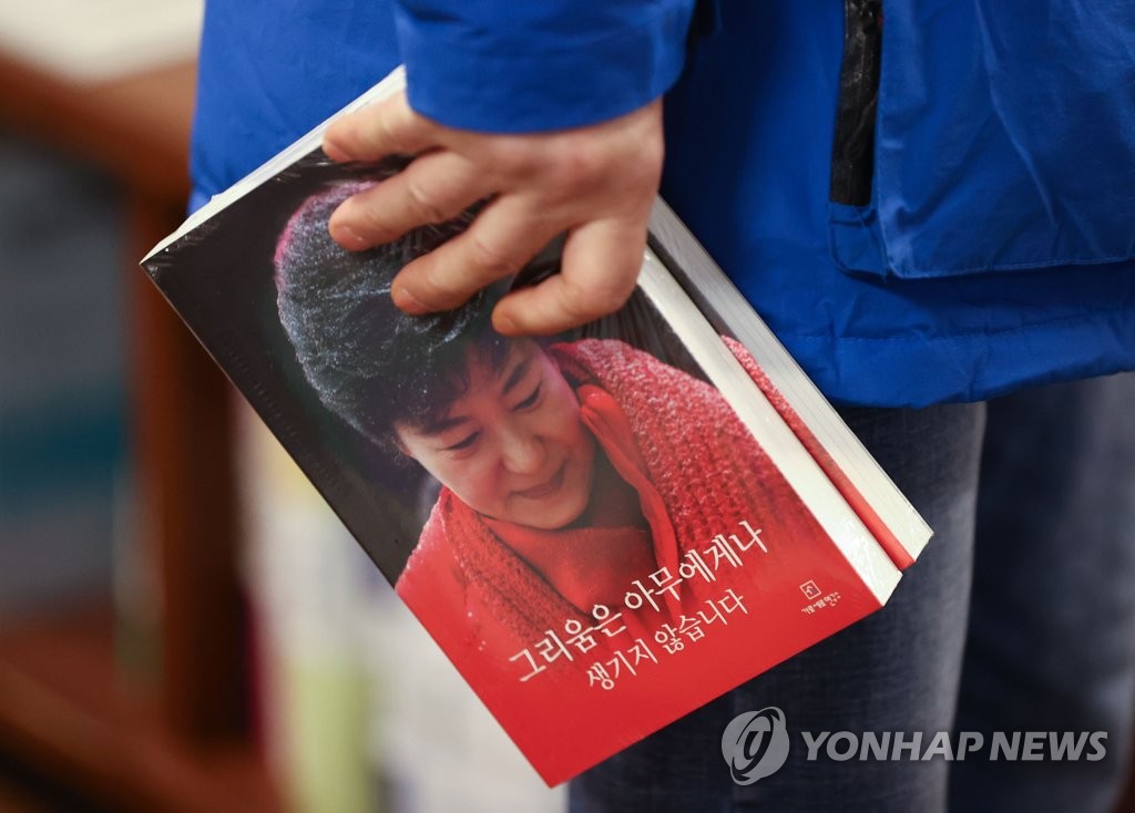 A customer holds a copy of former President Park Geun-hye's new book, "Not everybody feels a longing," at a bookstore in Seoul on Dec. 30, 2021. (Yonhap)