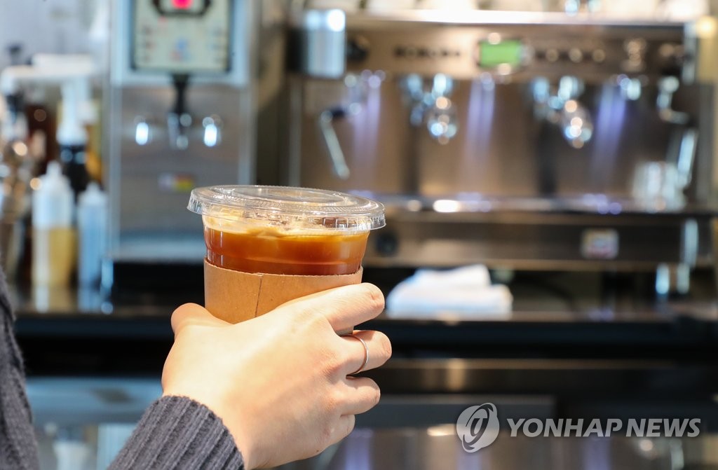 This Jan. 6, 2022, file photo shows a person holding coffee in a plastic cup at a cafe in Seoul. (Yonhap)