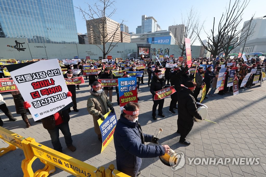 A group of small merchants holds a rally in downtown Seoul on Jan. 7, 2022, calling for the government to make up for their losses incurred from business restrictions under tough social distancing rules amid the pandemic. (Yonhap)