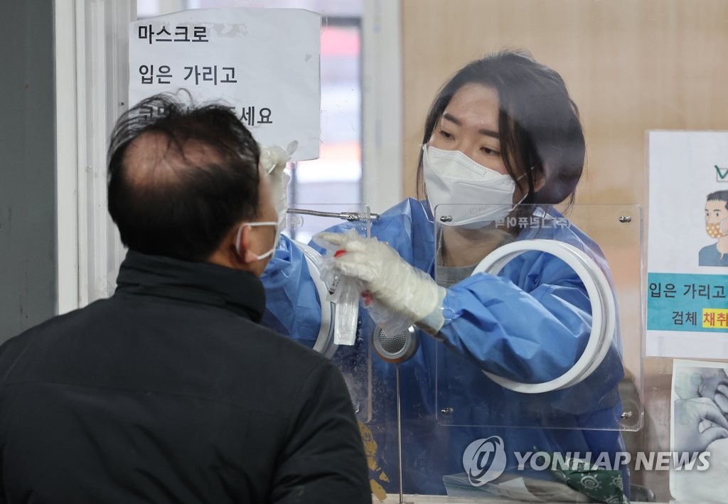 Une membre du personnel médical effectue un test de dépistage du nouveau coronavirus (Covid-19) le dimanche 9 janvier 2022 dans le centre sur la place de la gare de Séoul. 