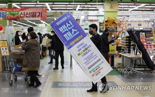 Un employé d'un magasin Hanaro Mart dans l'arrondissement de Seocho à Séoul retire une affiche concernant le passe vaccinal, après que la Cour administrative de Séoul a suspendu l'application du programme de passe vaccinal décrété par le gouvernement dans les grands magasins et supermarchés, le vendredi 14 janvier 2022.