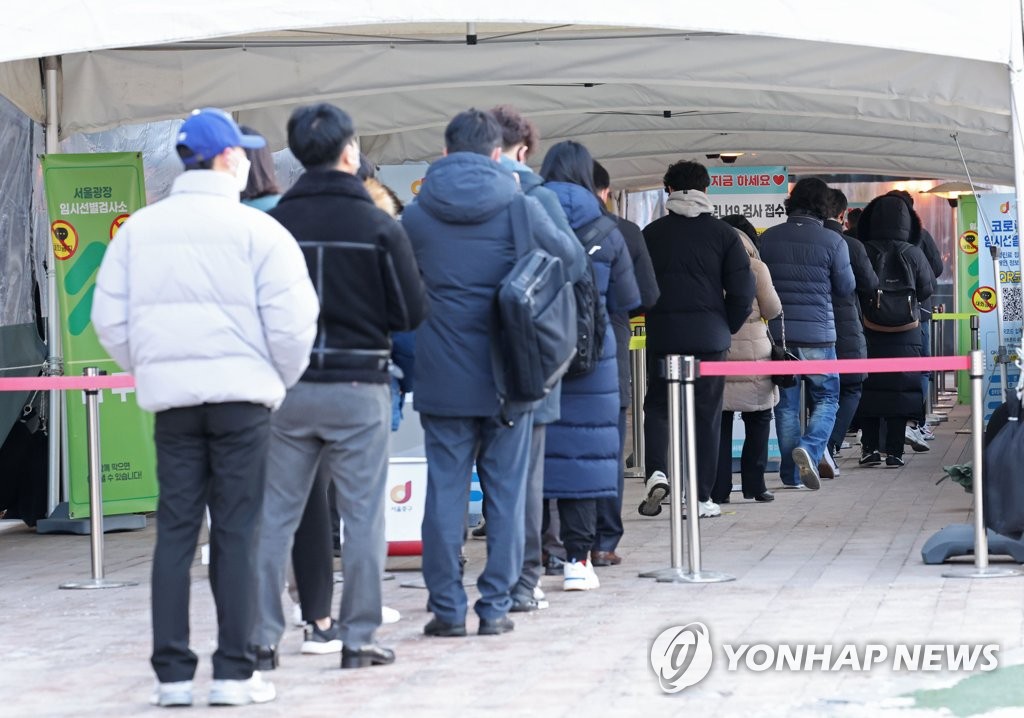 Las personas esperan en fila para someterse a la prueba del coronavirus, el 18 de enero de 2022, en un centro provisional de exámenes de COVID-19, frente al Ayuntamiento de Seúl, en la capital surcoreana.
