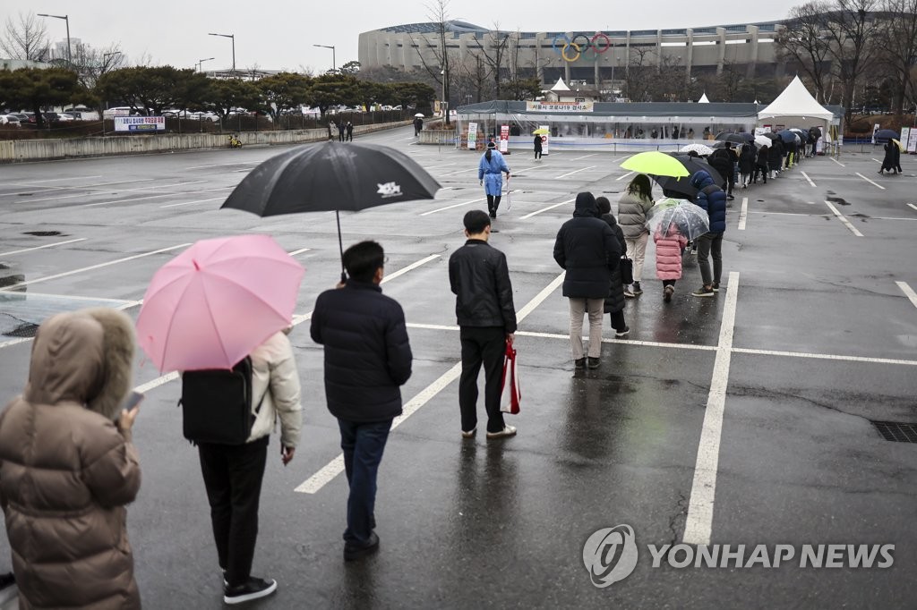 People wait in line to get tested for COVID-19 at a makeshift testing booth set up at a parking lot of the Jamsil Olympic Stadium in Seoul's eastern district of Songpa, on Jan. 25, 2022. (Yonhap)