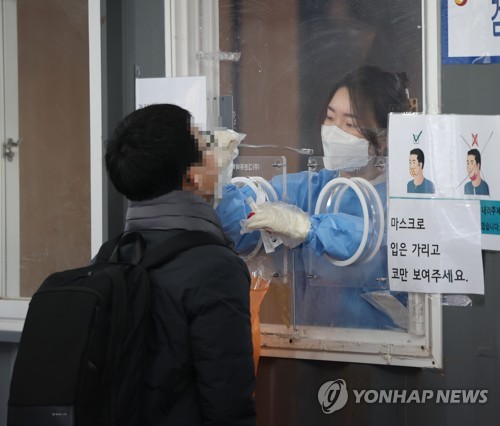 A medical worker carries out a COVID-19 test on a man at a makeshift testing station at Seoul Station in Seoul on Jan. 28, 2022. (Yonhap) 
