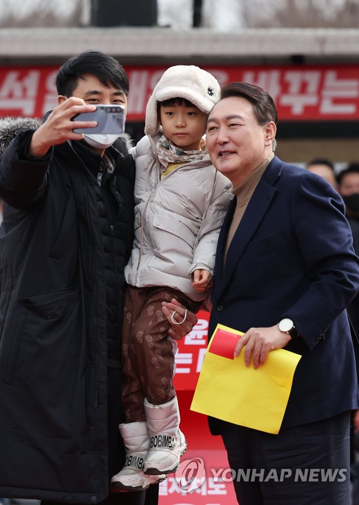 Yoon Suk-yeol (R), the presidential candidate of the main opposition People Power Party, poses for a photo with a boy after he was presented with a drawing by the boy during a campaign stop in Gangneung, Gangwon Province, on South Korea's east coast on Feb. 28, 2022, ahead of the March 9 election. (Pool photo) (Yonhap)
