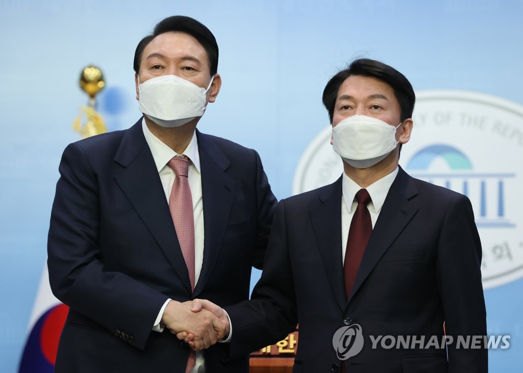 Yoon Suk-yeol (L), the presidential candidate of the main opposition People Power Party, poses for a photo with Ahn Cheol-soo of the minor opposition People's Party after the two announced a merger agreement at the National Assembly in Seoul on March 3, 2022. (Pool photo) (Yonhap)