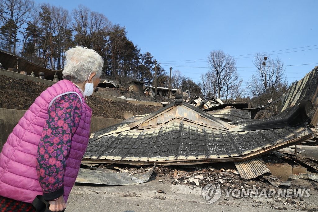 An elderly woman looks at her wildfire-ravaged house in Uljin, North Gyeongsang Province, on March 6, 2022. (Yonhap)