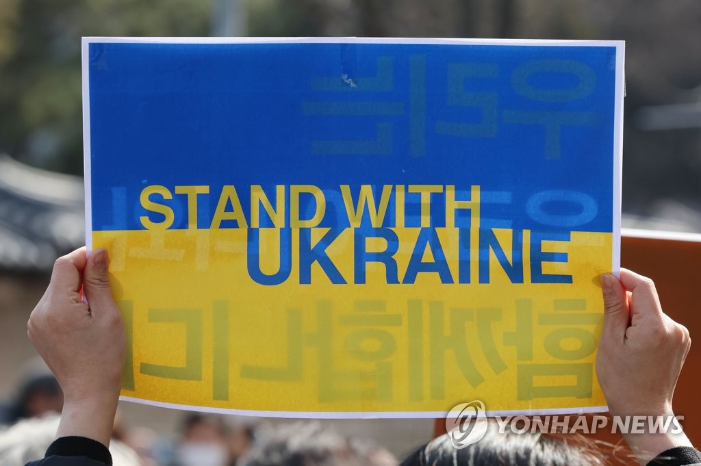 In this file photo, a protestor holds up a sign reading "Stand with Ukraine" as a group of female activists stages a rally in Seoul on March 8, 2022, to voice their objection to the Russian invasion of the Eastern European country as part of activities to mark International Women's Day. (Yonhap)