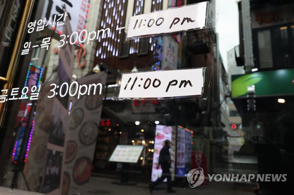 En el escaparate de una tienda de Seúl se informa, el 18 de marzo de 2022, el cierre del negocio a las 11:00 p.m. por el toque de queda comercial.