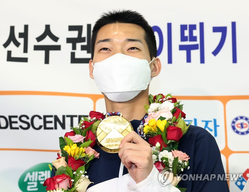 South Korean high jumper Woo Sang-hyeok holds up his gold medal won at the World Athletics Indoor Championships in Belgrade after arriving at Incheon International Airport, west of Seoul, on March 22, 2022. (Yonhap)