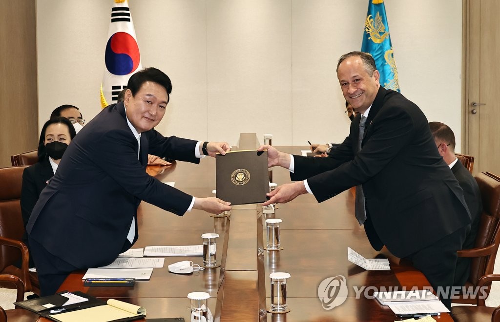 South Korean President Yoon Suk-yeol (L) poses for a photo while receiving U.S. President Joe Biden's personal letter to him from U.S. second gentleman Douglas Emhoff at his office in Seoul on May 10, 2022. Emhoff, leading a congratulatory group, attended Yoon's inaugural ceremony earlier in the day. (Yonhap)