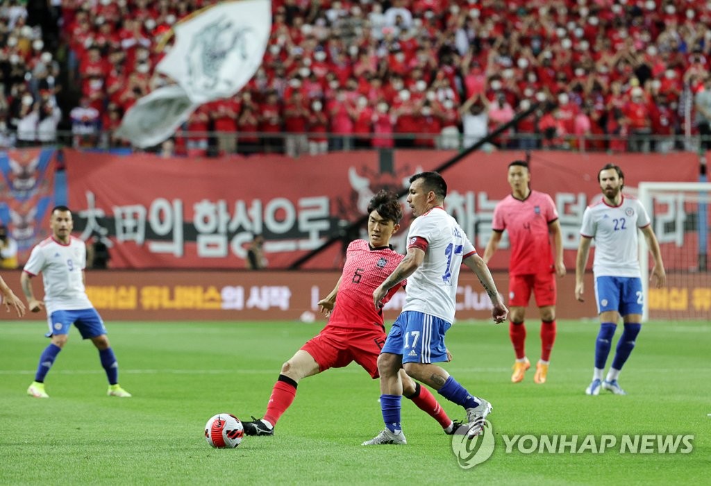 Hwang In-beom of South Korea (L) tries to make a pass past Gary Medel of Chile during the countries' friendly football match at Daejeon World Cup Stadium in Daejeon, 160 kilometers south of Seoul, on June 6, 2022. (Yonhap)