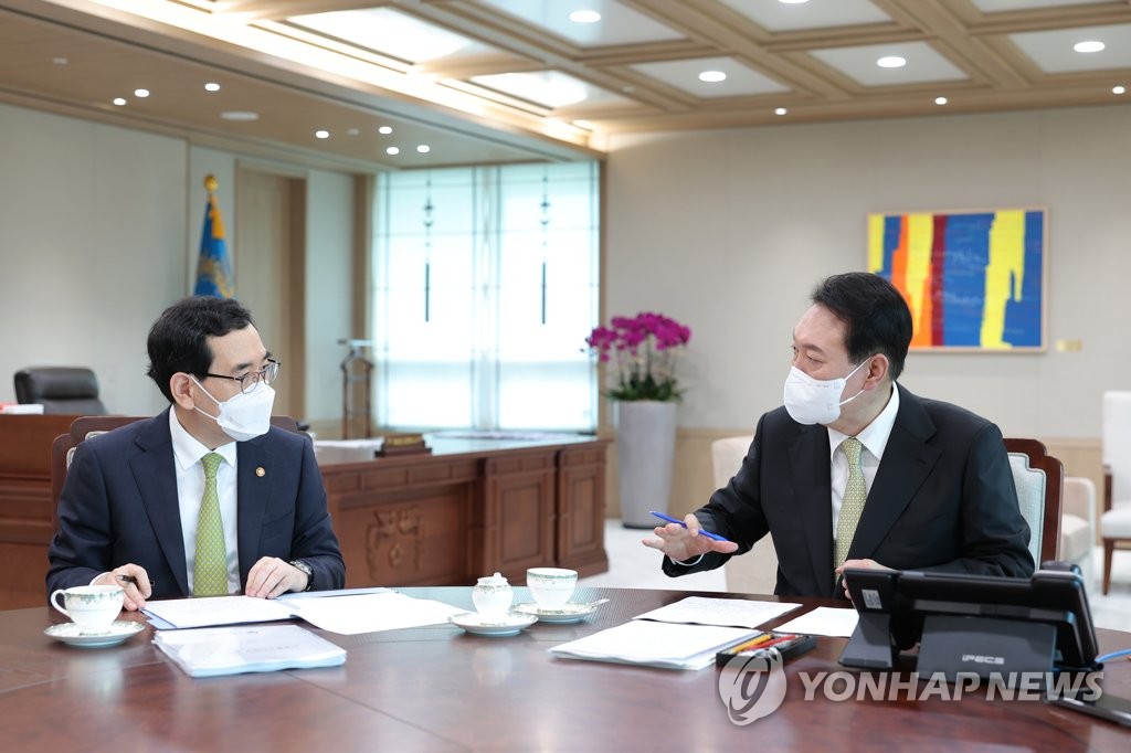 La foto, proporcionada por la oficina presidencial, muestra al presidente surcoreano, Yoon Suk-yeol (dcha.), recibiendo un informe de políticas por parte del ministro de Comercio, Industria y Energía, Lee Chang-yang, el 12 de julio de 2022, en su oficina, en Seúl. (Prohibida su reventa y archivo)