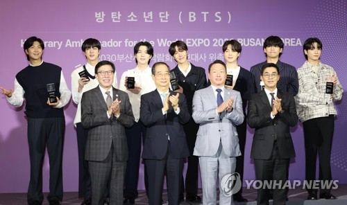 ＢＴＳは７月に、３０年釜山万博誘致の広報大使に就任した。委嘱式で記念撮影するＢＴＳ（後列）と朴市長（前列左端）ら関係者（資料写真）＝（聯合ニュース）