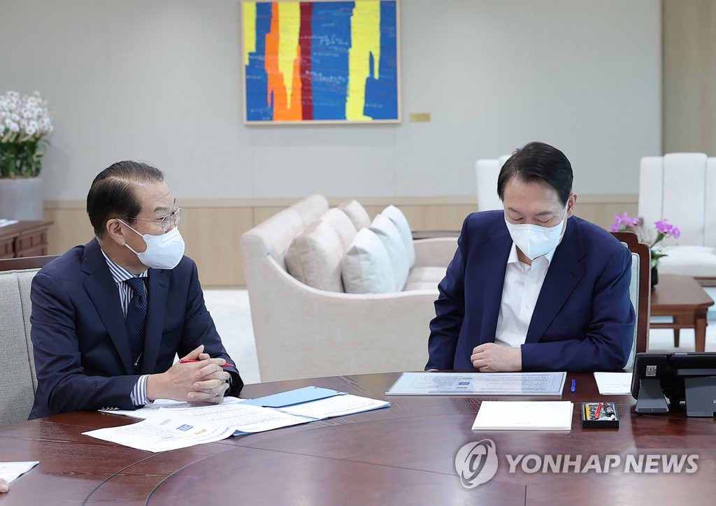 President Yoon Suk-yeol (R) receives a policy report from Unification Minister Kwon Young-se at the presidential office in Seoul on July 22, 2022, in this photo released by the office. (PHOTO NOT FOR SALE) (Yonhap)