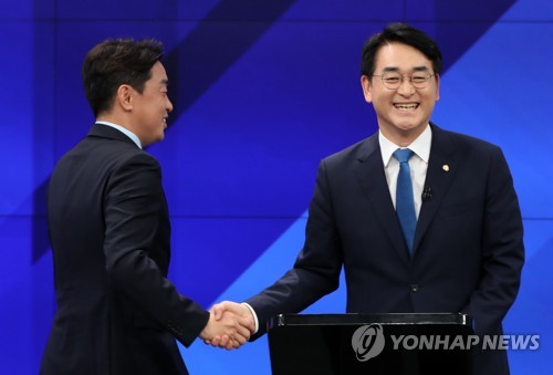 Rep. Kang Hoon-sik (L) and Rep. Park Yong-jin of the main opposition Democratic Party shake hands in a chairmanship candidate debate hosted by local television outlet G1 in Chuncheon, Gangwon Province, in this Aug. 2, 2022, file photo. 