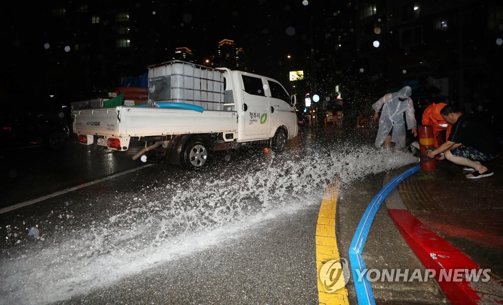 침수된 도로에서 물 빼내는 시민과 소방관