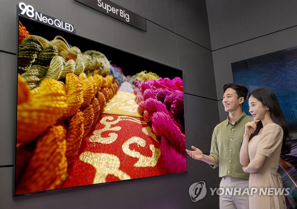 La foto, proporcionada por Samsung Electronics Co., muestra a modelos observando un televisor Neo QLED de 98 pulgadas de la compañía, en una tienda de la empresa, en el distrito de Gangnam, en el sur de Seúl. (Prohibida su reventa y archivo)