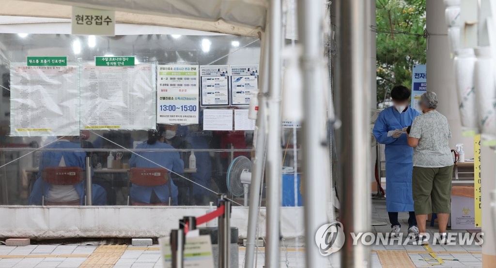 Un trabajador médico habla a un visitante, el 28 de septiembre de 2022, en una clínica provisional de exámenes de COVID-19 en un centro de salud comunitario en el distrito de Mapo, en Seúl.