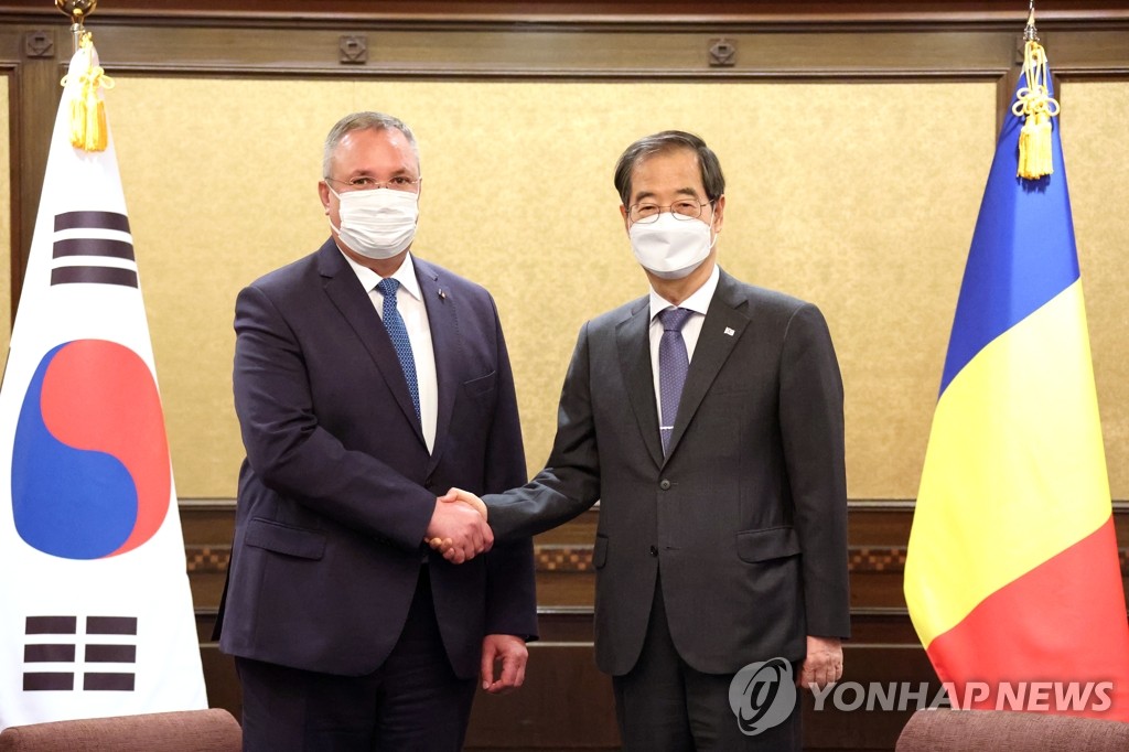 El primer ministro de Corea del Sur, Han Duck-soo (dcha.), estrecha la mano de su homólogo rumano, Nicolae Ciuca, antes de sus conversaciones sostenidas, el 28 de septiembre de 2022, en un hotel de Tokio, Japón. 
