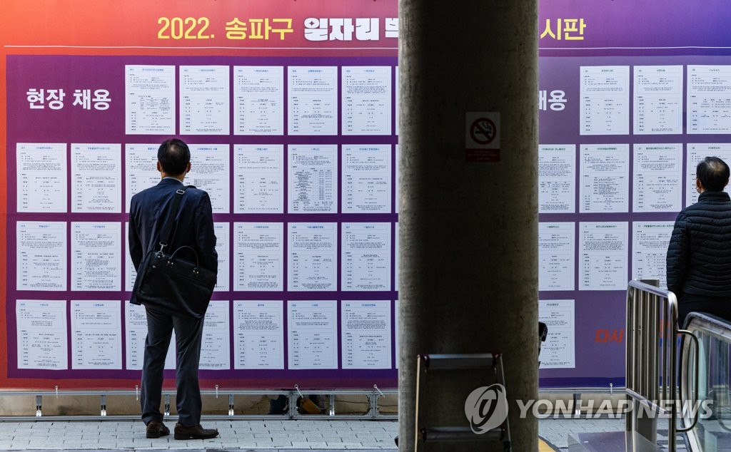 Los demandantes de empleo leen, el 19 de octubre de 2022, un boletín con anuncios de trabajo, en una feria de empleo, en Seúl. 
