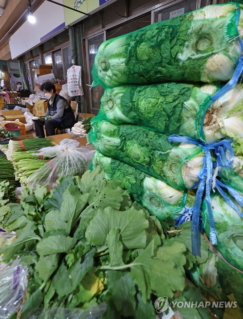 Korean cabbages and other vegetables for "gimjang," or making kimchi, a traditional Korean side dish normally made of fermented cabbage, are stacked at a traditional market in Seoul on Oct. 25, 2022.