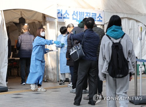 Medical workers help visitors take coronavirus tests at a public health facility in Seoul's Nowon Ward on Nov. 21, 2022. South Korea's new COVID-19 cases hit around 23,000, on par with the level a week earlier, amid growing worries over yet another virus wave in the winter. (Yonhap)