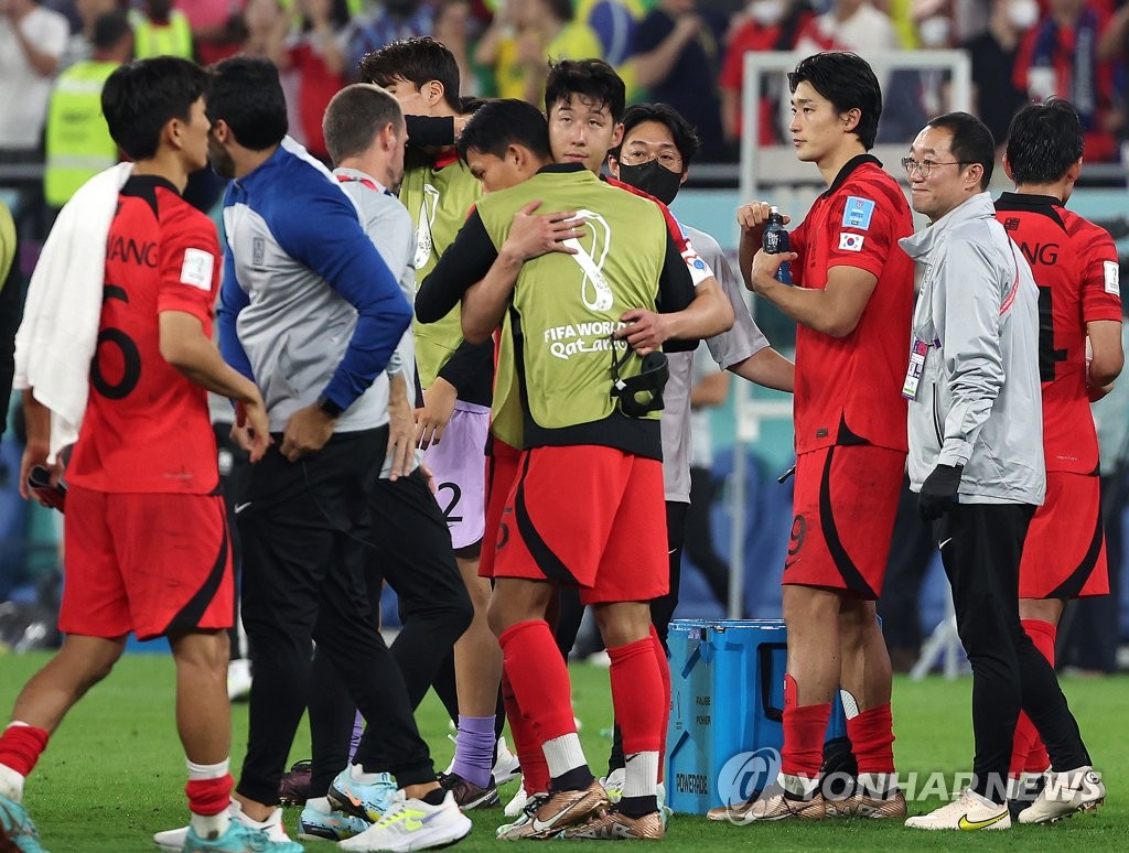 South Korean players and coaches console each other after losing to Brazil 4-1 in the round of 16 at the FIFA World Cup at Stadium 974 in Doha on Dec. 5, 2022. (Yonhap)