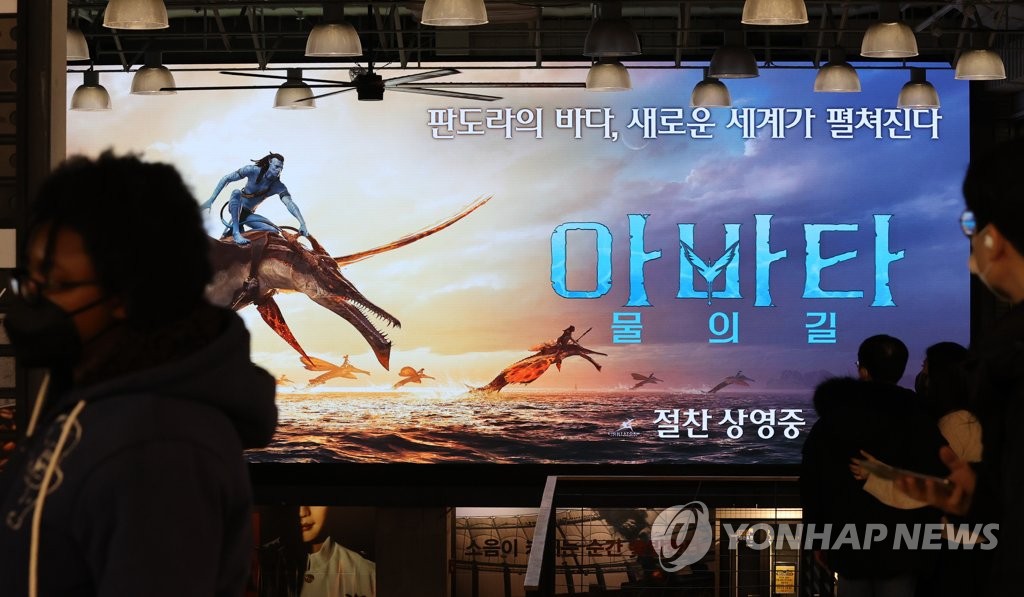 People pass by the poster of "Avatar: The Way of Water" at a Seoul theater on Dec. 18, 2022. (Yonhap)