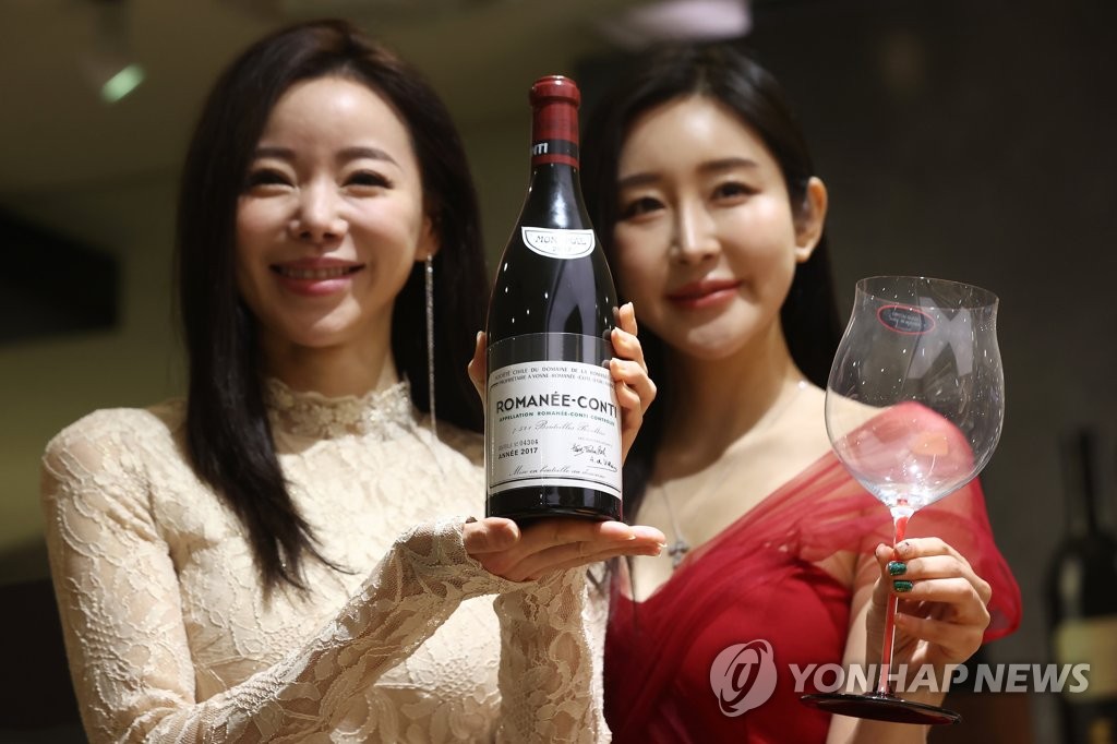 En esta fotografía de archivo, tomada el 12 de enero de 2023, unas modelos posan con una botella de vino en los Grandes Almacenes Lotte, en el centro de Seúl.