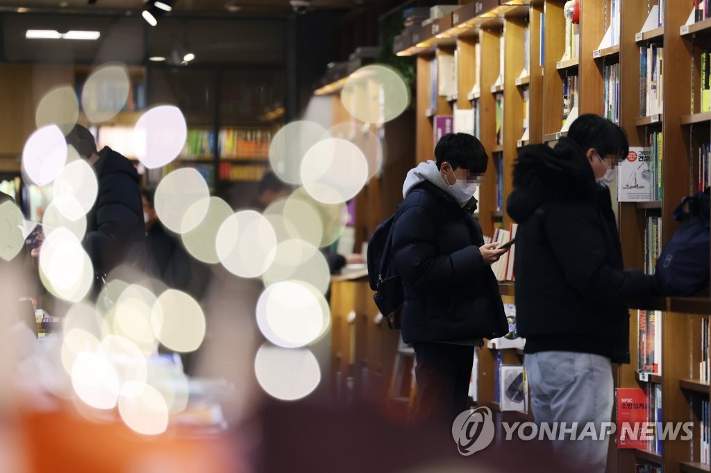 Las personas leen libros usando mascarillas en una librería de Seúl, el 20 de enero de 2023, mientras se espera que se levante, el 30 de enero, el mandato del uso obligatorio de las mascarillas en lugares públicos bajo techo.