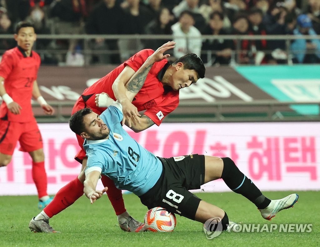 Kim Min-jae of South Korea (top) gets tangled up with Maxi Gomez of Uruguay during the countries' friendly football match at Seoul World Cup Stadium in Seoul on March 28, 2023. (Yonhap)