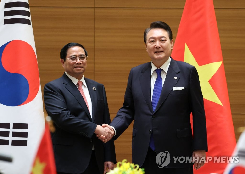 South Korean President Yoon Suk Yeol (R) shakes hands with Vietnamese Prime Minister Pham Minh Chinh at their summit at a hotel in Hiroshima, Japan, on May 19, 2023. (Yonhap)