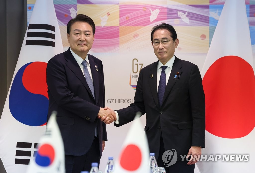 Pietų Korėjos prezidentas Yun Sok Yul (L) ir Japonijos ministras pirmininkas Fumio Kishida paspaudžia vienas kitam ranką per viršūnių susitikimą Hirosimoje, Japonijoje, šioje 2023 m. gegužės 21 d.  Sekite mėgstamiausią